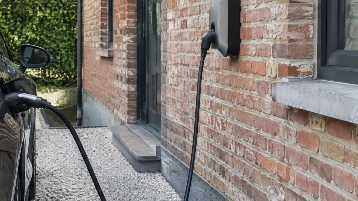 Laadpaal aan een gevel met aangesloten elektrische wagen